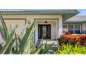 Inviting front entrance with a black front door, side lights, and well manicured landscape at 3445 Highlands Bridge Rd, Sarasota, FL 34235