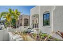 Elegant white stucco home featuring an arched entryway, complemented by vibrant landscaping at 422 Burns Ct, Sarasota, FL 34236