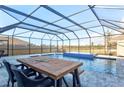 Relaxing screened-in pool area with stylish pavers, waterfall feature, and dining table at 5117 Sultana Cv, Bradenton, FL 34211