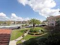 Scenic view from the unit overlooking well-manicured lawn, palm trees, and covered parking at 6501 Stone River Rd # 205, Bradenton, FL 34203