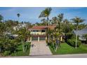 Bright and welcoming home with a two-car garage, manicured lawn, and mature palm trees at 691 Linley St, Longboat Key, FL 34228