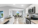 Contemporary kitchen with stainless steel appliances, open to a dining area with verdant backyard views at 128 Sequoyah Dr, Port Charlotte, FL 33954