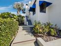 Exterior view of a white condo featuring blue awnings and lush landscaping at 2012 Harbourside Dr # 2104, Longboat Key, FL 34228