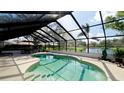 Screened pool and deck overlooks a pond, with lounge furniture and lush landscaping around the pool deck at 3610 Garden Lakes Clenet, Bradenton, FL 34203