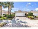 Home featuring a two-car garage with a brick-paved driveway and meticulous landscaping at 5907 Guarino Dr, Sarasota, FL 34238