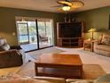 Comfortable living room featuring a ceiling fan, entertainment center, and sliding glass doors to the screened porch at 1842 Country Meadows Ct, Sarasota, FL 34235
