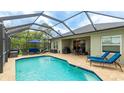 A screened pool with an outdoor patio is furnished with a seating set, grill, and lounge chairs at 3839 Autumn Fern Ter, Sarasota, FL 34243