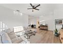 Bright living room with modern fan, recessed lights, neutral sectional, glass table, and light wood floors at 4414 Turnberry Ct, Bradenton, FL 34210