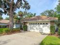 Two-car garage with decorative windows and mature landscaping surrounding the driveway at 5708 Garden Lakes Fern, Bradenton, FL 34203