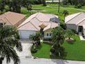 Aerial view of a well-maintained home with a tile roof, lush landscaping, and a two-car garage at 8503 Gateway Ct, Englewood, FL 34224
