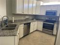 Bright kitchen features white cabinets, stainless steel appliances, granite counters, and tile flooring at 12229 Amica Loop, Venice, FL 34293