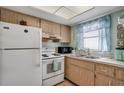 Bright kitchen featuring white appliances, wood cabinets, and a window with blue curtains at 2907 51St W Ave, Bradenton, FL 34205