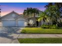 Charming single-story home with a red tile roof, manicured lawn and mature palm trees at dusk at 4705 Sweetmeadow Cir, Sarasota, FL 34238