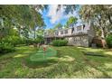 Spacious backyard with putting green, screened in porch, mature trees, and lush landscaping at 5504 Beneva Woods Circle, Sarasota, FL 34233