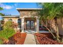 The front of the house with double glass doors, stone columns and tropical landscaping at 5814 117Th E Ter, Parrish, FL 34219