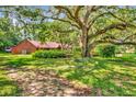 Home featuring mature landscaping with grand old oak tree and covered in spanish moss at 805 Mcarthur Ave, Sarasota, FL 34243