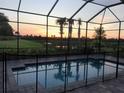 Screened pool overlooking lush green space with sunset views and pool safety fence at 8901 Artisan Way, Sarasota, FL 34240