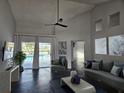 Bright living room with stylish decor, sleek black floors, vaulted ceilings, fan, and sliding doors to the pool at 1211 Peridot Lane, Sun City Center, FL 33573