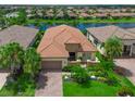 Stunning aerial view of a home with a red tile roof, lush landscaping, and a serene lake backdrop at 13214 Treviso Dr, Bradenton, FL 34211
