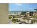 Beach view from the balcony showing the ocean, beach, palm trees, parking and the condo building at 1945 Gulf Of Mexico Dr # M2-516, Longboat Key, FL 34228