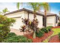 Beautiful home showcasing an attached garage, lush landscaping, and a paver driveway at 19962 Benissimo Dr, Venice, FL 34293