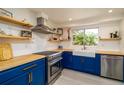 Bright kitchen featuring blue cabinets, butcher block countertops, stainless steel appliances, and open shelving at 4210 Pandora Rd, Venice, FL 34293