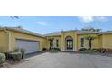 Single Gathering home featuring a two-car garage, arched entrance, and manicured landscaping at 6114 Misty Oaks St, Sarasota, FL 34243
