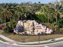 Scenic entrance to River Strand featuring a decorative rock waterfall and lush greenery at 6560 Willowshire Way, Bradenton, FL 34212