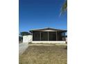 A bright home featuring a screened porch and utility shed, with a clear blue sky at 197 Palm Harbor Dr, North Port, FL 34287