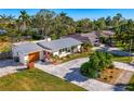 Beautiful aerial view of home with a metal roof, updated landscaping, a long driveway and lots of mature trees at 2341 Siesta Dr, Sarasota, FL 34239