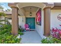 Inviting front porch with decorative columns, a colorful door, and a whimsical pink chair at 2625 Yuma Ave, North Port, FL 34286