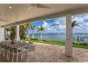 Covered patio with comfortable outdoor seating, overlooking a landscaped backyard and picturesque waterfront at 2828 Riverview Blvd, Bradenton, FL 34205