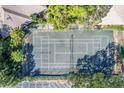 Aerial view of fenced tennis court surrounded by lush, mature trees, close to parking at 3330 Thornwood Rd # 3330, Sarasota, FL 34231