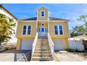 Inviting two-story yellow home with bright white trim, an impressive staircase, and dual garages with a spacious driveway at 4117 Roberts Point Cir, Sarasota, FL 34242