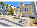 Charming yellow two-story home featuring an inviting white staircase, lush landscaping, and an attached garage with a spacious driveway at 4117 Roberts Point Cir, Sarasota, FL 34242