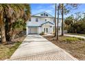 Inviting elevated home featuring a white exterior and a blue roofline, complemented by well-maintained landscaping at 527 Magnolia Ave, Anna Maria, FL 34216