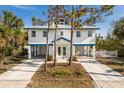 Inviting elevated home featuring a white exterior and a blue roofline, complemented by well-maintained landscaping at 527 Magnolia Ave, Anna Maria, FL 34216
