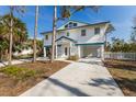 Inviting elevated home featuring a white exterior and a blue roofline, complemented by well-maintained landscaping at 527 Magnolia Ave, Anna Maria, FL 34216