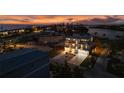 A nighttime aerial view of a white three-story home with well-lit interiors, a double garage, and manicured landscaping at 597 Buttonwood Dr, Longboat Key, FL 34228