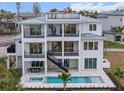 Modern three-story home with outdoor staircase, balconies, a pool, and spa, perfect for luxury living and entertaining at 597 Buttonwood Dr, Longboat Key, FL 34228