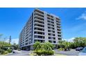 Low angle view of the condo building displaying balconies and mature landscaping at 6415 Midnight Pass Rd # 910, Sarasota, FL 34242