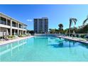 Large community pool with lounge chairs, umbrellas, and a view of the condo buildings at 6415 Midnight Pass Rd # 910, Sarasota, FL 34242