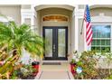 Close-up of front door with decorative glass, potted plants, American flag, and Ring doorbell for added security at 7601 226 E St, Bradenton, FL 34211