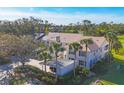 Aerial view of the condo building with landscaping including palm trees and tiled roof at 801 Montrose Dr # 202, Venice, FL 34293