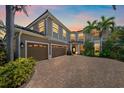 Beautiful two-story house with a paved driveway, three-car garage, lush landscaping, and warm, inviting lighting at 820 Placid Lake Dr, Osprey, FL 34229
