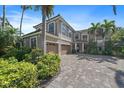 Beautiful two-story house featuring a three-car garage, lush landscaping, and a patterned brick driveway at 820 Placid Lake Dr, Osprey, FL 34229