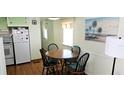 Cozy dining area featuring a round table, four chairs, wood floors and a delightful tropical themed painting at 10315 Cortez W Rd # 28-1, Bradenton, FL 34210