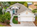 Inviting single-Gathering home with a blue front door, lush landscaping, and a brick driveway leading to a two-car garage at 12211 Lavender Loop, Bradenton, FL 34212