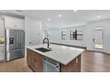Bright open-concept kitchen featuring stainless steel appliances, a central island, and wood flooring throughout at 18803 Dayspring Pl, Venice, FL 34293