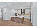 Modern kitchen with white cabinets, stainless steel appliances, large island, and stylish backsplash at 18803 Dayspring Pl, Venice, FL 34293